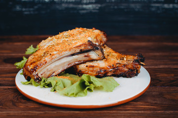 Delicious barbecued pork ribs served on lettuce on an old rustic wooden board