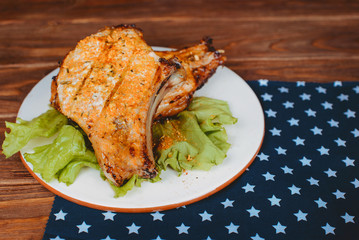 Delicious barbecued pork ribs served on lettuce on an old rustic wooden board