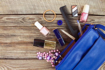 Things from open lady handbag. women's purse on wood background. Cosmetics and women's accessories...