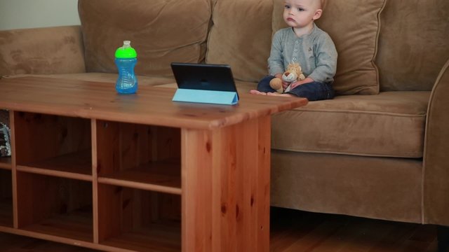 a baby boy watching show on a tablet