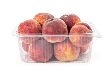 Box or punnet of fresh ripe organic peaches isolated on white background