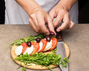 Mozzarella cheese with tomatoes and olives on wooden table