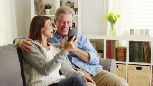 Senior couple using smartphone on couch