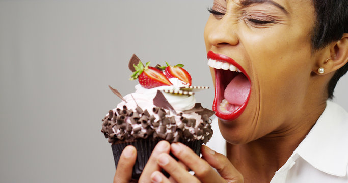 Black woman taking a huge bite out of a fancy dessert