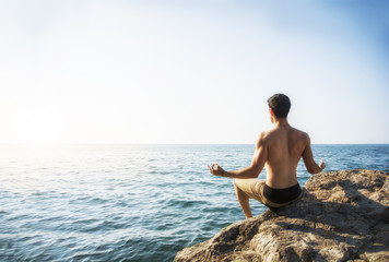 Young Man Meditating or Doing Yoga Exercise by Sea