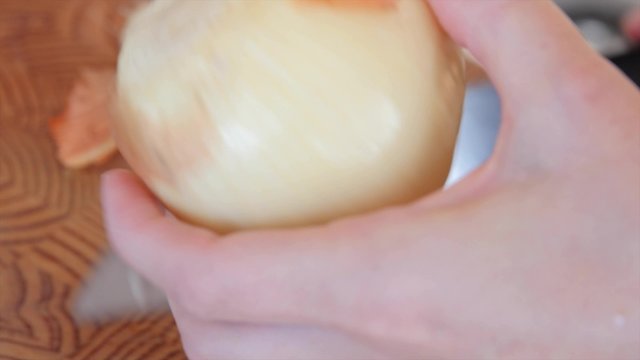 A woman cuts an onion on a cutting board