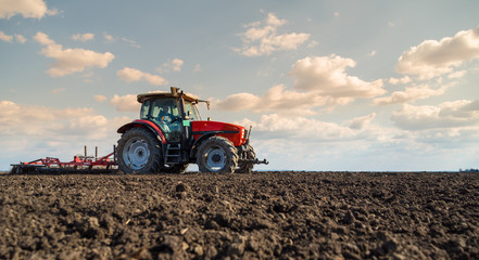 Obraz premium Farmer in tractor preparing land with seedbed cultivator