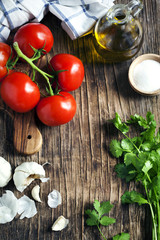 Fresh tomatoes, garlic and cilantro on wooden background