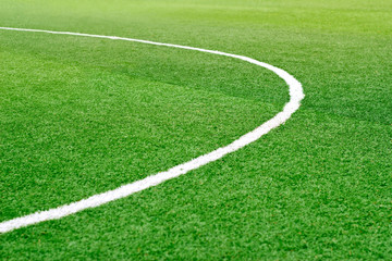 Fototapeta na wymiar Green soccer field grass with white mark line, soft focus