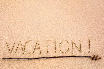 Inscription of Vacation written on wet yellow beach sand with ar