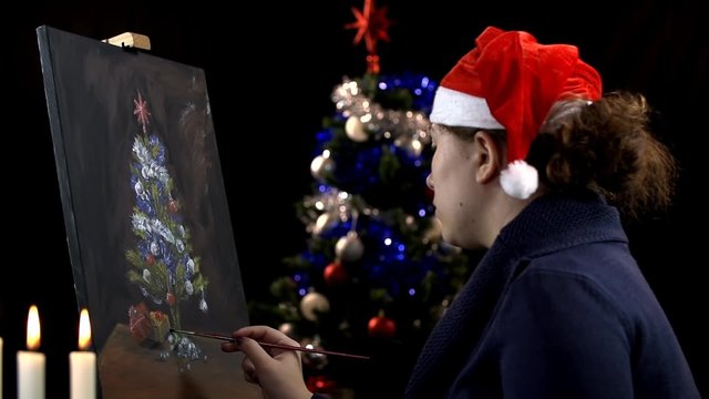 Artist with Santa hat checking Christmas tree painting