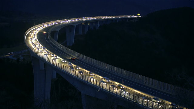Curved viaduct highway at night with traffic jam