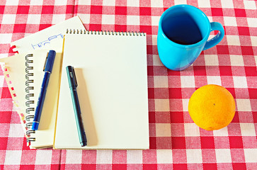 Vintage editable notebook on the red table, with a bright cup of coffee and a fruit.