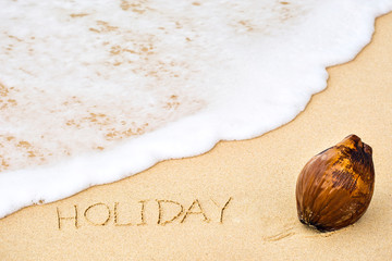 Inscription of word Holiday written on wet yellow beach sand and