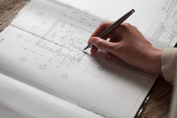 woman holding a pen over a house blueprint