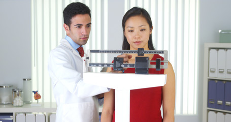 Mexican doctor weighing Chinese patient