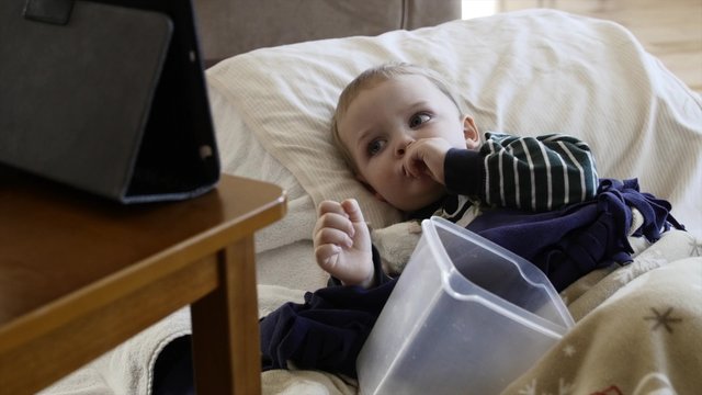 A sick little boy with the flu on the floor watching movie