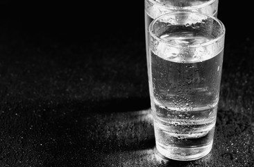 Two glasses of gin on a dark background, black and white, select