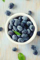 Honeysuckle berries in bowl on wooden surface
