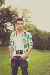 Trendy young man with analog camera outdoors