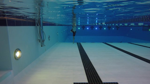 An underwater shot man swimming toward a camera