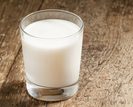 A glass of fresh milk on old wooden table, selective focus