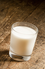 A glass of fresh milk on old wooden table, selective focus