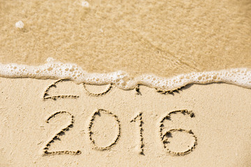 2015 2016 inscription written in the wet yellow beach sand being