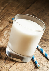 A glass of fresh milk with striped blue and white tubes on an ol