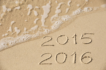 2015 2016 inscription written in the wet yellow beach sand being