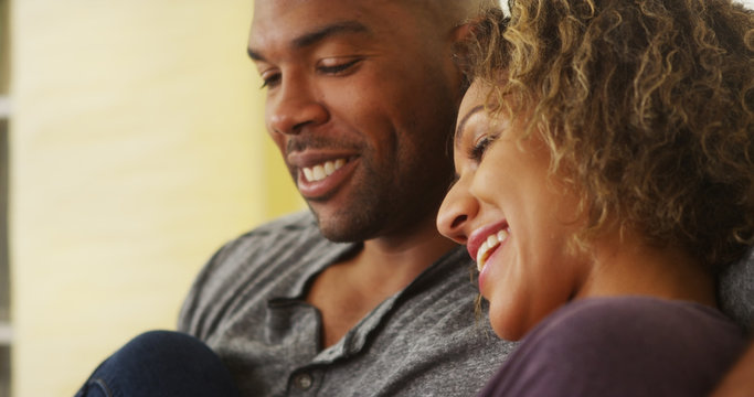 Black couple sitting on couch smiling