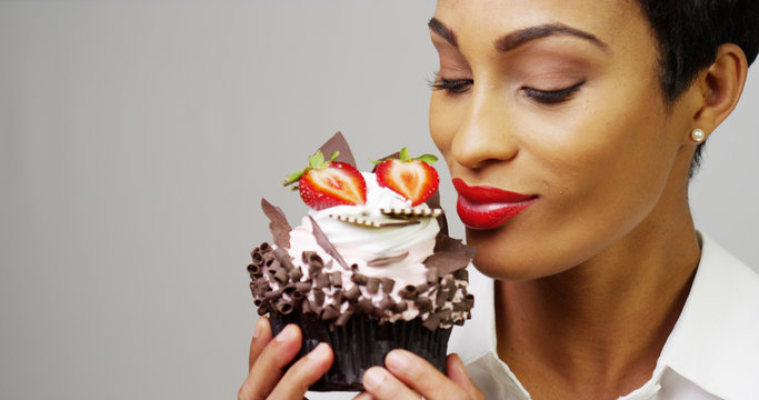 Woman admiring a fancy dessert cupcake with chocolate and strawberries