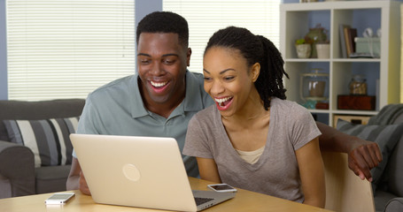 Young black couple watching funny video on laptop