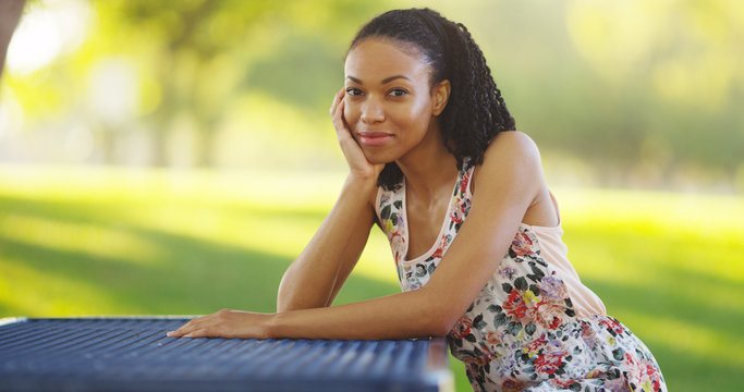 Black woman sitting on a park bench smiling