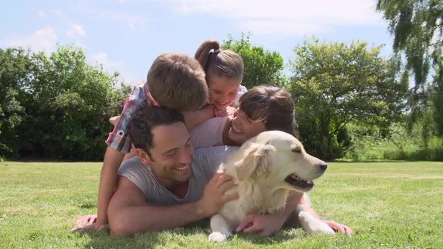 Family Relaxing In Garden With Pet Dog
