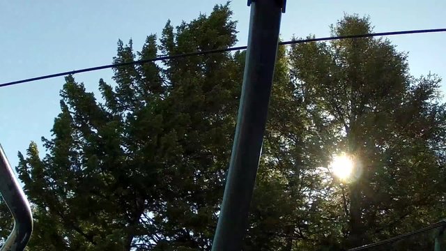 sun behind trees on ski chair lift