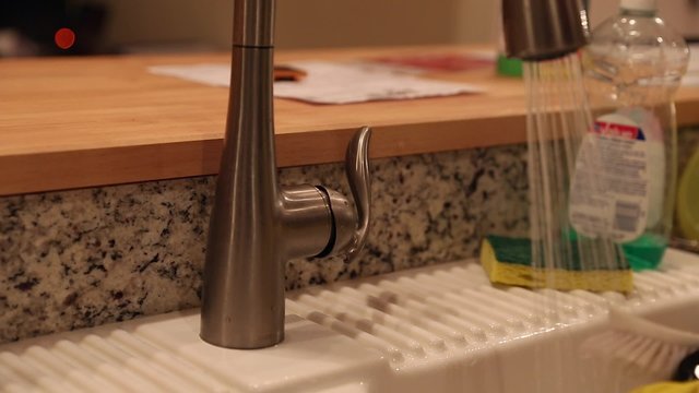 pregnant woman washing dishes in the kitchen sink