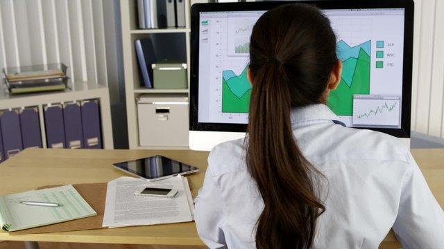 Hispanic businesswoman analyzing charts on computer