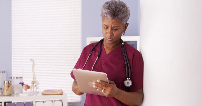 Mature Black Woman Doctor Working On Tablet In Office