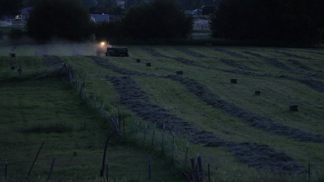 Farmer bailing hay in evening