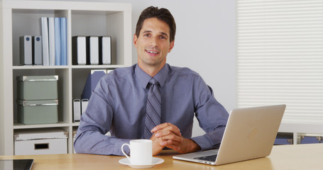Businessman sitting at desk and talking to camera