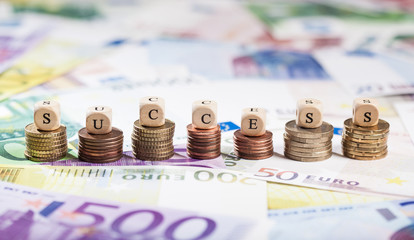 Word Success on coin stacks, cash background