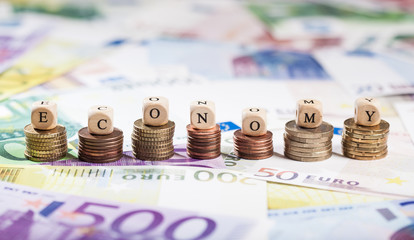 Word Economy on coin stacks, cash background