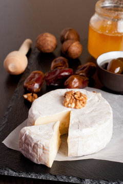 Camembert with honey, dates and nuts on dark background