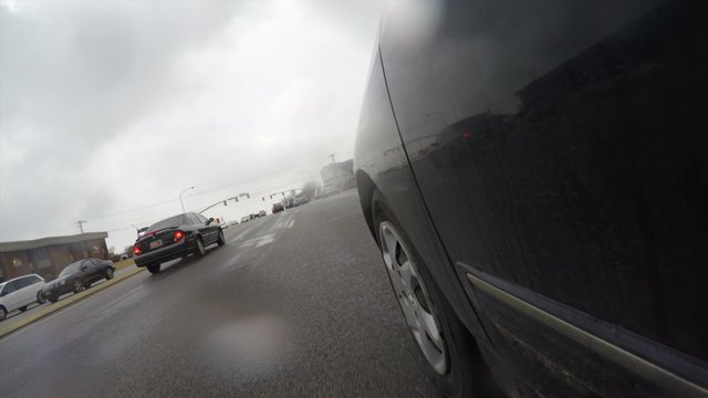 Exterior low shot cars driving in Provo city Utah through rain