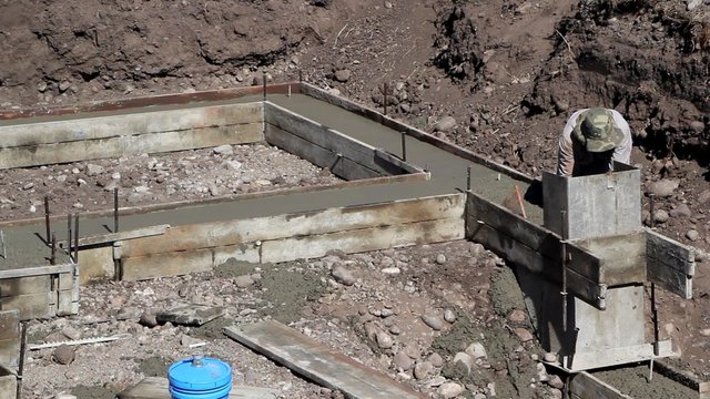 Man smoothing out cement footings