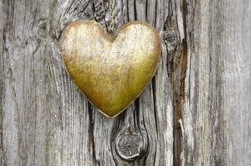 Herz aus Metall hängt an einem verwitterten Holzbrett