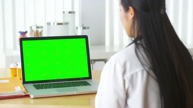 Asian doctor talking to laptop with green screen