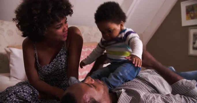 Family With Baby Son Bouncing On Bed Together