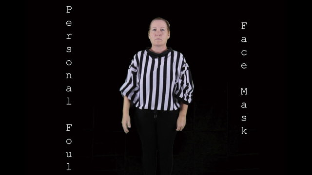 Woman dressed as a football referee signaling Face Mask.